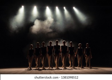 Ballet Class On The Stage Of The Theater With Light And Smoke. Children Are Engaged In Classical Exercise On Stage.