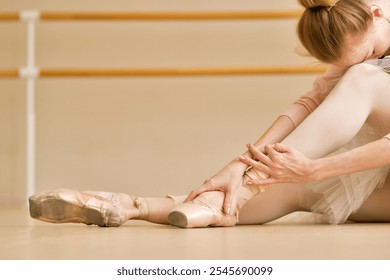 Ballet dancer adjusting her pointe shoes, with focus on her hands and feet. - Powered by Shutterstock