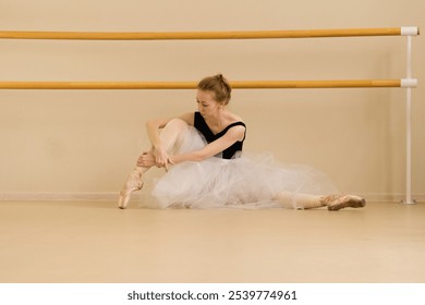 A ballet dancer adjusts her attire while seated, demonstrating focus and elegance. - Powered by Shutterstock