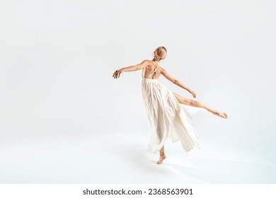 Ballet dancer dancing over studio background in maxi dress. Back view. Copy space. Full length. 