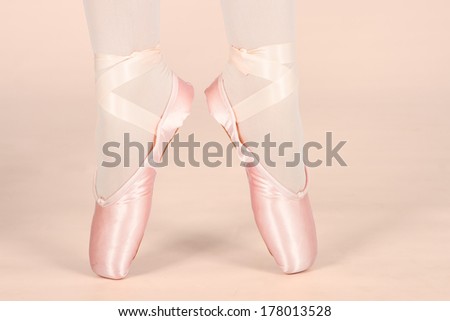 A ballet dancer standing on toes while dancing on peach background artistic conversion