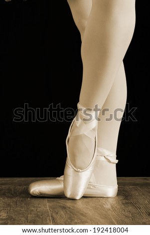 A ballet dancer standing on toes while dancing on black background artistic conversion