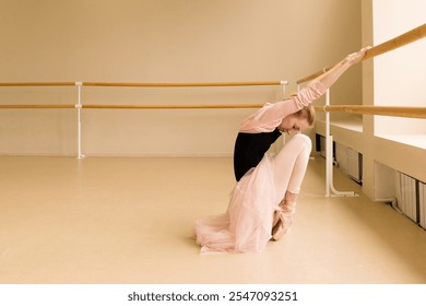 Ballet dancer stretching at barre in studio, dressed in pink and black. - Powered by Shutterstock