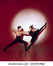 Ballet dancers dancing over red studio background. Modern design. Contemporary colorful conceptual light as rising sun at Japan. Female and male perfomers in japanese makeup. Shadow from silhouettes