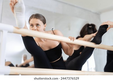 Ballet dancers warm up at the barre in the dance studio - Powered by Shutterstock