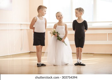 At ballet dancing class: young boys and a girl with flowers posing gracefully