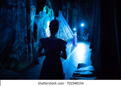 ballet, dancing, magic concept. in ghostly blue light decoration for perfomance and tender silhouette of slender ballerina wearing pink dress with short sleeves waiting for her turn backstage