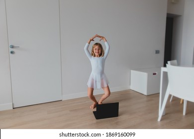 Ballet lesson online. Little girl dancing while looking at computer at home.