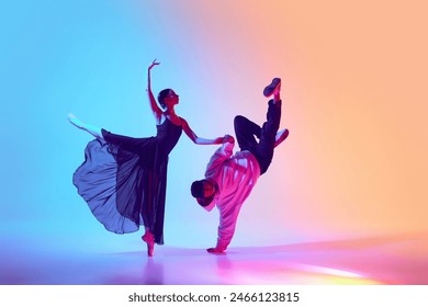 Ballet and street dance mix. Beautiful young girl in black dress, ballerina dancing with young man, hip hop performer on gradient background in neon. Concept of classical and modern dance, performance - Powered by Shutterstock