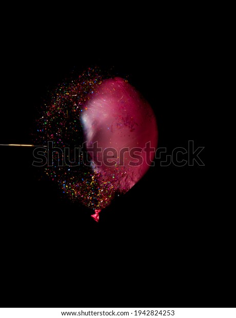 A\
Balloon filled with glitter being pierced by a\
dart.