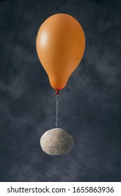 Balloon flying stone on dark background. Overcoming difficulties or inspiration concept