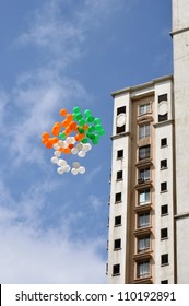Balloons in the colors of the flag soaring into the sky along a high rise apartment building