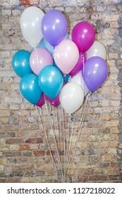 A lot of balloons at front of bricks wall.