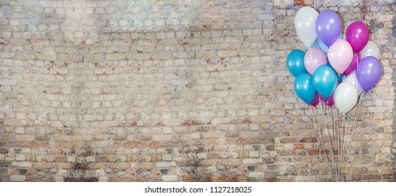 A lot of balloons at front of bricks wall.