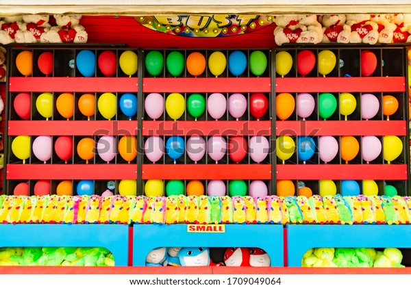 balloons and prizes at a dart\
throwing game booth at a carnival, fair, or amusement park in\
America