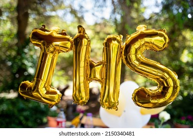 Balloons In The Shape Of The Letters IHS, Referring To The Sacrament Of First Holy Communion. In The Background, An Outdoor Party For Children. IHS 