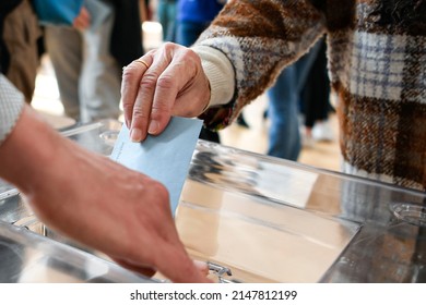 A ballot paper in its envelope, held in the hand by a lady, just before being placed in the ballot box