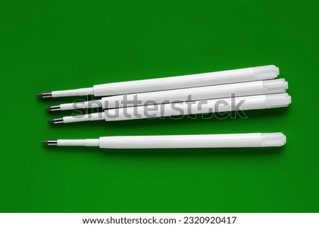 Ballpoint pen refills. Plastic rods for a ballpoint pen. White ink refills on a green background