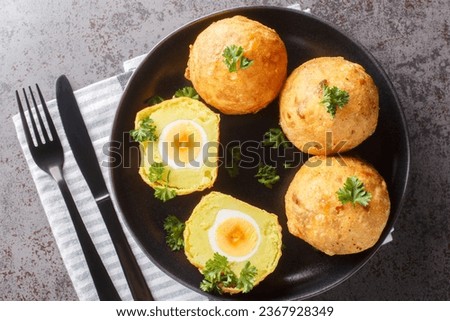 Balls of mashed potatoes stuffed with boiled egg and then fried close-up in a plate on the table. Horizontal top view from above