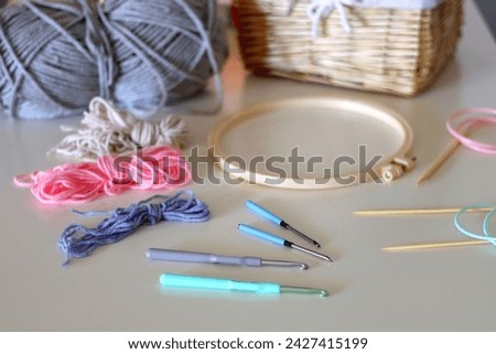 Balls of yarn, threads, various needlecraft needles and lit candles on the table. Hygge at home. Selective focus.