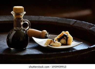 Balsamic Vinegar of Modena with Parmesan flakes set on plates and a wooden barrel 