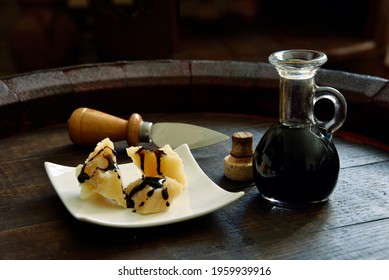 Balsamic Vinegar of Modena with Parmesan flakes set on plates and a wooden barrel