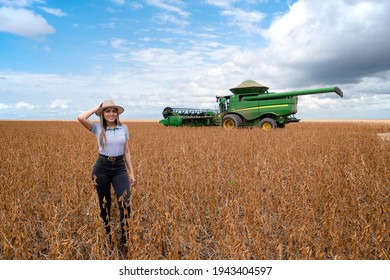 BALSAS - MARANHÃO, BRAZIL - MARCH 17, 2021: Luana Nunes With Her Hand On The Hat Representing The Strength Of The Woman In The Field Beside A John Deere Harvester