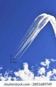 Baltic aerobatic team performs precision formation flying stunt with coordinated smoke trails against blue sky