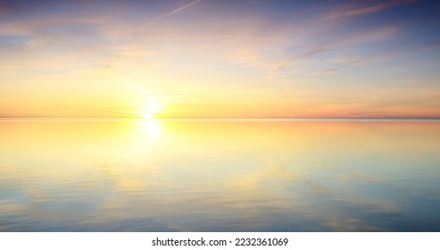 Baltic sea after the rain. Dramatic sunset sky, glowing pink and golden clouds, symmetry reflections in the water. Abstract natural pattern, texture, background. Picturesque panoramic scenery