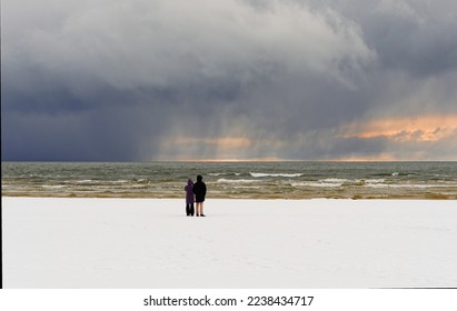 Baltic Sea beach in snowy winter. Falling snow from the clouds.
