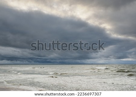 Baltic sea during the storm. Dramatic sky, dark glowing clouds. Waves, water splashes. Idyllic seascape. Climate change, nature, fickle weather, ecology