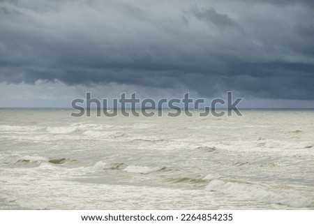 Baltic sea during the storm. Dramatic sky, dark glowing clouds. Waves, water splashes. Idyllic seascape. Climate change, nature, fickle weather, ecology