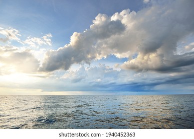 Baltic sea shore after the storm. Dramatic sunset sky, glowing clouds, golden sunlight. Waves, splashing water. Picturesque panoramic scenery, seascape, cloudscape. Nature, environment, ecology