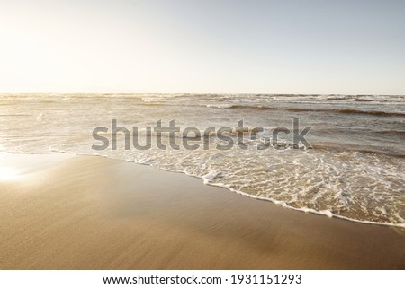 Baltic sea shore (sand dunes) at sunset. Soft sunlight, clear sky, waves and water splashes. Idyllic seascape. Latvia, Europe. Spring, weather, climate change, nature. Panorama, copy space
