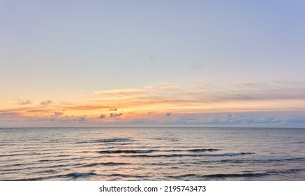 Baltic sea shore at sunset. Clear sky, glowing clouds, soft golden sunlight, midnight sun. Dreamlike seascape. Panoramic view. Pure nature, tourism, summer vacations, weekend getaway concepts
