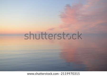 Baltic sea at sunset. Clear sky, blue and pink glowing clouds, soft golden sunlight. Water surface texture. Picturesque dreamlike seascape, cloudscape, nature. Panoramic view
