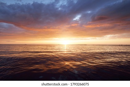 Baltic sea at sunset. Dramatic sky with glowing clouds reflecting in the water. Lighthouse in the background. Setting sun. Epic seascape. Abstract natural pattern, texture, background, concept image - Powered by Shutterstock