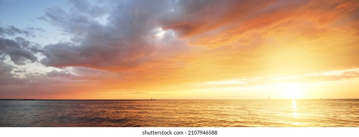 Baltic sea at sunset. Dramatic sky with glowing golden pink clouds, reflections in the water. Lighthouse. Setting sun. Epic seascape. Abstract natural pattern, texture, background, concept image - Powered by Shutterstock