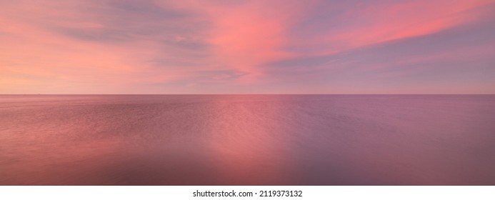 Baltic sea under the colorful sunset sky. Stunning seascape. Golden sunset light through the pink clouds. Long exposure. Tranquility scene. Riga bay, Latvia