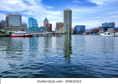 Baltimore Inner Harbor water view with shopping centers and cruise boats near National Aquarium and downtown business district buildings and shops in a cityscape skyline of the scenic Maryland city