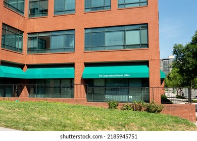 Baltimore, Maryland US - June 25, 2022: Bland Grass Lawn And Undersized Shrubs Landscaping In Front Of All Brick Building, With Ground Floor Office Of 7th Congressional District On Green Awning