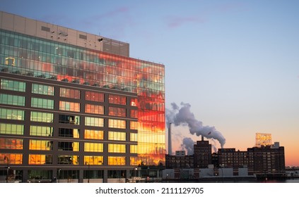 Baltimore, Maryland, USA - January 22, 2022: A colorful sunset reflects off the Canopy by Hilton at Harbor Point. The Domino Sugar factory can be seen in the lower right-hand corner. 