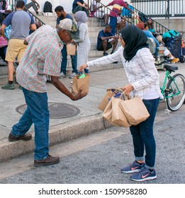 Baltimore, MD/USA - Sept 7th 2019: Act of Kindness Homeless Care Package Muslim Woman Hijabi Homeless Man at the steps of a Church 