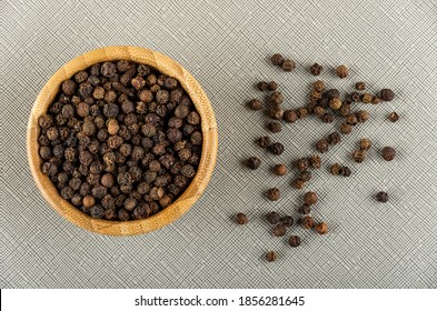 Bamboo Bowl With Peppercorn, Scattered Black Pepper On Gray Table . Top View