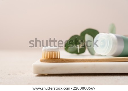 Bamboo brush with toothpaste close-up view on marble stand. Dental concept