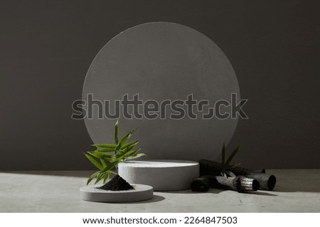 Bamboo charcoal and bamboo leaves surround the circular platform, creating space for the product or design, front view on dark background