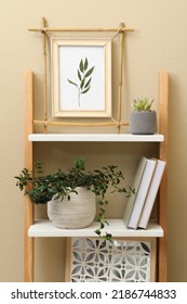 Bamboo Frame And Different Decor Elements On Shelving Unit Near Beige Wall