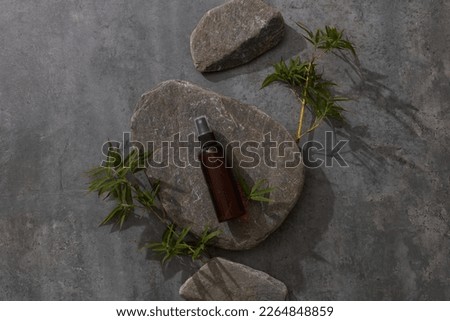 Bamboo leaves and grey stone as podium for cosmetic presentation on dark background, top view.