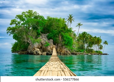 Bamboo pedestrian hanging bridge over sea to remote desert island. Beautiful tropical landscape. Travel lifestyle. Wild nature vacations. Adventure ecotourism concept. Way to Paradise. Exotic scenery