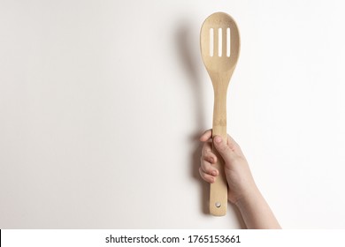 
Bamboo Spoon In A Children's Hand On A White Background. A Child Is Holding A Bamboo Spoon - Top View.